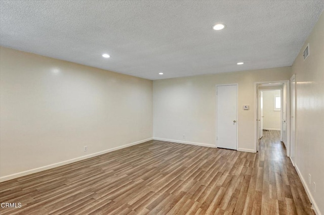 spare room featuring wood finished floors, a textured ceiling, recessed lighting, and baseboards
