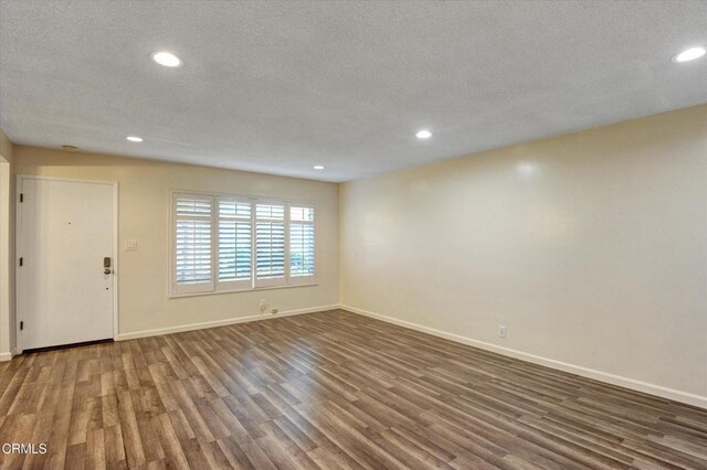 unfurnished living room featuring wood finished floors, recessed lighting, baseboards, and a textured ceiling