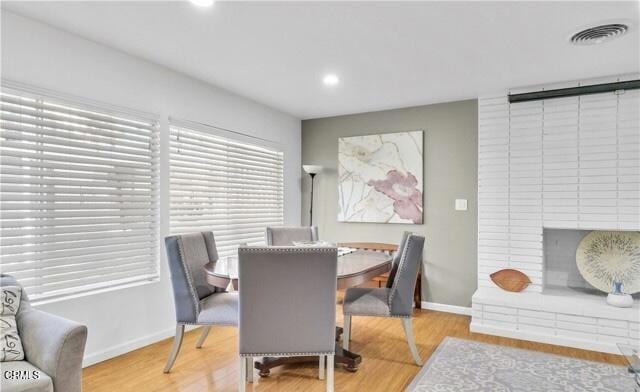 dining room featuring light wood finished floors, baseboards, a fireplace, and recessed lighting