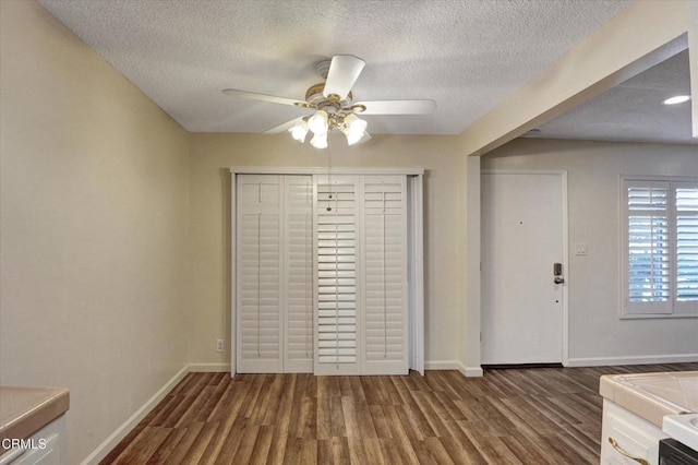 foyer entrance featuring ceiling fan, wood finished floors, baseboards, and a textured ceiling