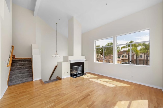 11354 Via Rancho San Diego Unit J, El Cajon, CA 92019 - unfurnished living room with light wood-style floors, high vaulted ceiling, baseboards, a fireplace with flush hearth, and stairs
