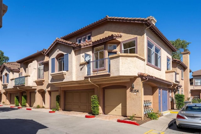 11354 Via Rancho San Diego Unit J, El Cajon, CA 92019 - view of front facade featuring a balcony, a garage, stucco siding, and a tile roof