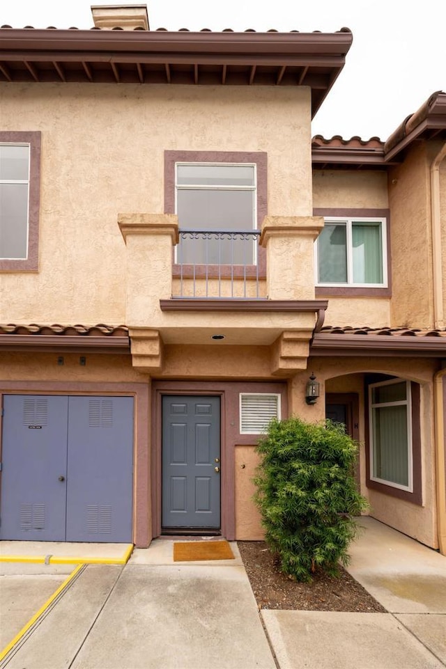 11354 Via Rancho San Diego Unit J, El Cajon, CA 92019 - entrance to property featuring a balcony, stucco siding, a tiled roof, and a chimney