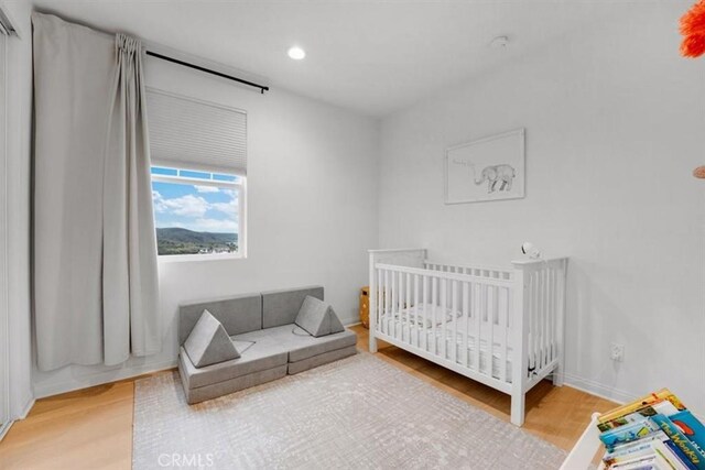 10243 Graphite St, Spring Valley, CA 91977 - bedroom featuring light wood-style flooring, recessed lighting, baseboards, and a crib