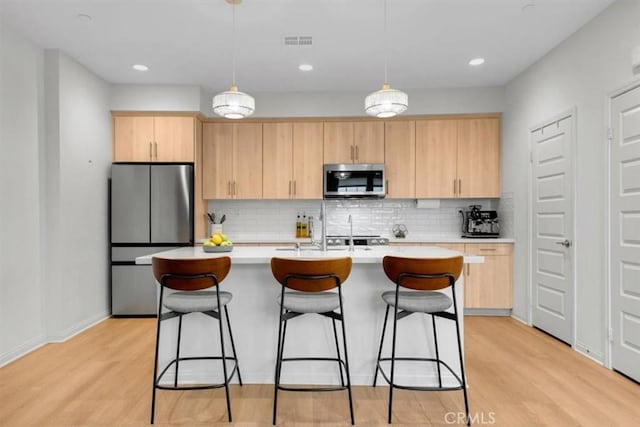 10243 Graphite St, Spring Valley, CA 91977 - kitchen with stainless steel appliances, light brown cabinetry, light countertops, a breakfast bar area, and recessed lighting