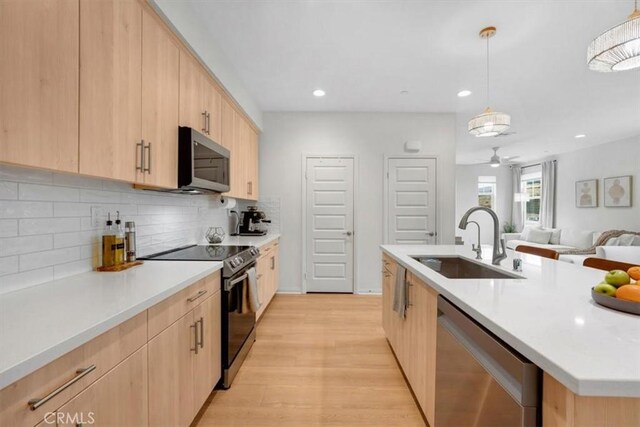10243 Graphite St, Spring Valley, CA 91977 - kitchen with light brown cabinetry, stainless steel appliances, a sink, light wood finished floors, and decorative backsplash