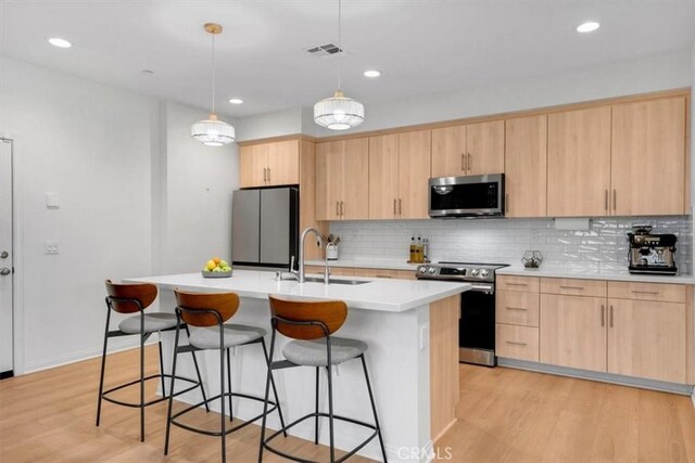10243 Graphite St, Spring Valley, CA 91977 - kitchen featuring appliances with stainless steel finishes, light brown cabinets, a sink, a breakfast bar area, and recessed lighting