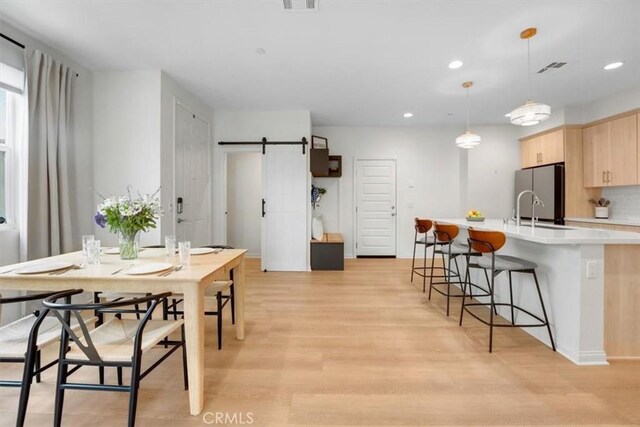 10243 Graphite St, Spring Valley, CA 91977 - kitchen with light brown cabinetry, light countertops, light wood finished floors, a breakfast bar area, and an island with sink