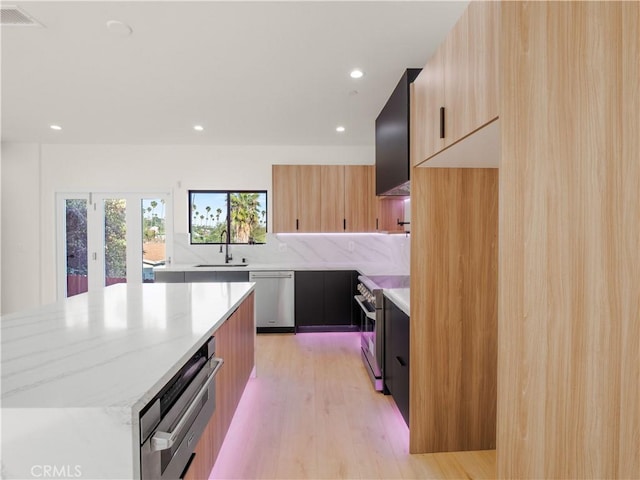 3810 Locke Ave, Los Angeles, CA 90032 - kitchen featuring modern cabinets, appliances with stainless steel finishes, a sink, light wood-style flooring, and light stone counters