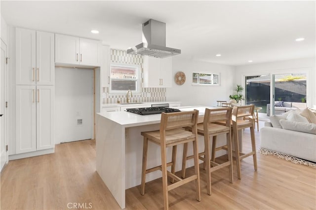 1825 W Carlton Pl, Santa Ana, CA 92704 - kitchen featuring wall chimney range hood, a sink, white cabinets, light wood finished floors, and light countertops