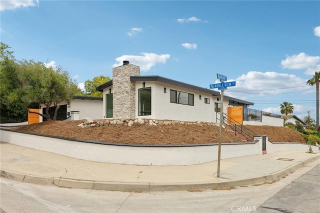 view of front of home featuring a chimney and stucco siding