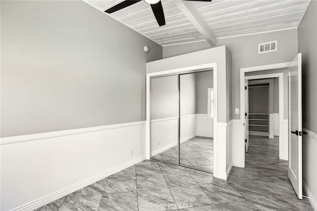 unfurnished bedroom featuring marble look tile flooring, a closet, beam ceiling, ceiling fan, and baseboards
