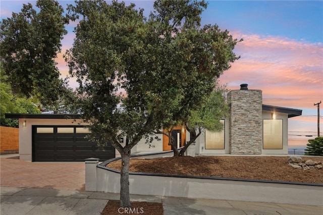 view of front facade with decorative driveway, a garage, and stucco siding