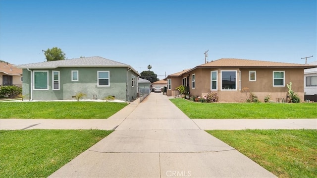 bungalow-style house with stucco siding, a front lawn, and driveway