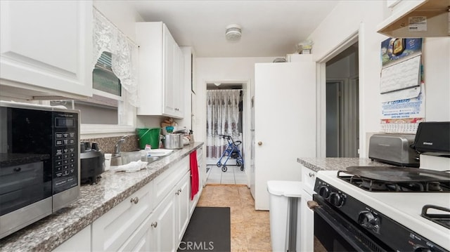 kitchen with stainless steel microwave, a sink, range with gas stovetop, and white cabinets