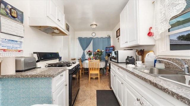 kitchen featuring black range with gas stovetop, white cabinets, and a sink