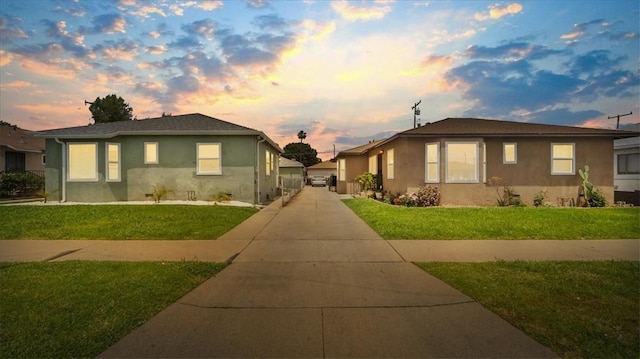 view of front of property with stucco siding, a lawn, and concrete driveway