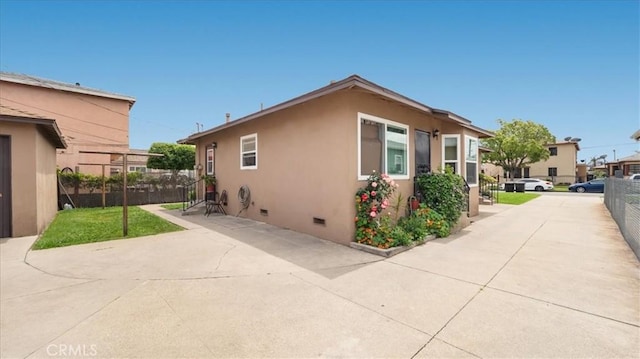 view of home's exterior with fence, crawl space, stucco siding, and a patio