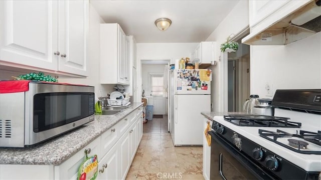 kitchen featuring range with gas cooktop, freestanding refrigerator, under cabinet range hood, stainless steel microwave, and white cabinetry