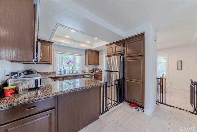 5855 Via Sonora Unit 39, Yorba Linda, CA 92887 - kitchen featuring appliances with stainless steel finishes, dark stone counters, a sink, a raised ceiling, and baseboards