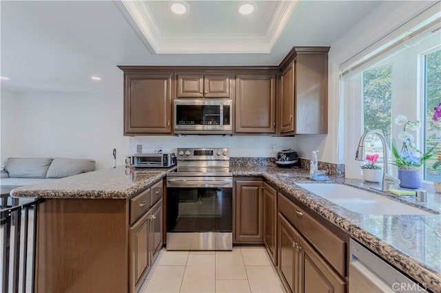 5855 Via Sonora Unit 39, Yorba Linda, CA 92887 - kitchen featuring appliances with stainless steel finishes, a sink, a tray ceiling, ornamental molding, and stone counters