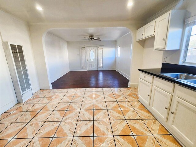 1210 W Manchester Ave, Los Angeles, CA 90044 - kitchen with arched walkways, a heating unit, dark countertops, light tile patterned flooring, and a ceiling fan