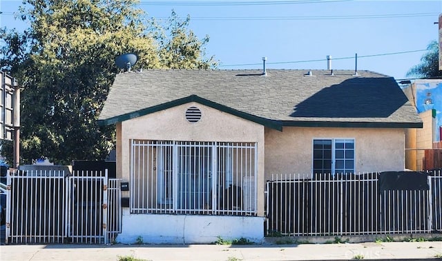 1210 W Manchester Ave, Los Angeles, CA 90044 - bungalow-style home featuring stucco siding, roof with shingles, and a fenced front yard