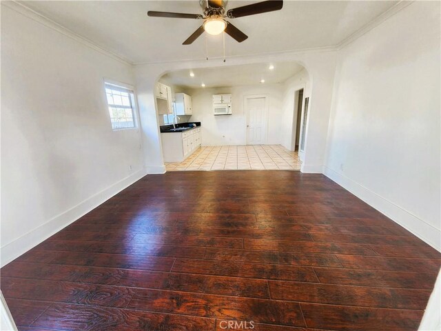 1210 W Manchester Ave, Los Angeles, CA 90044 - unfurnished living room featuring arched walkways, light wood-style floors, ornamental molding, a ceiling fan, and a sink