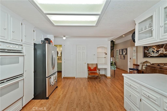 26349 Walnut Hills Dr, Lake Arrowhead, CA 92391 - kitchen featuring freestanding refrigerator, double oven, light wood-style floors, white cabinetry, and glass insert cabinets