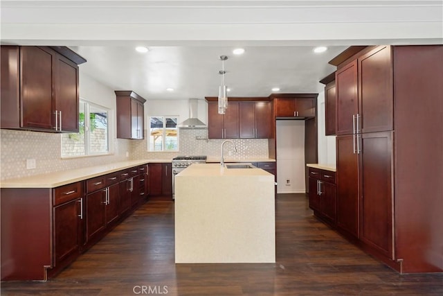 kitchen featuring wall chimney range hood, stainless steel range, a sink, dark wood-style flooring, and recessed lighting