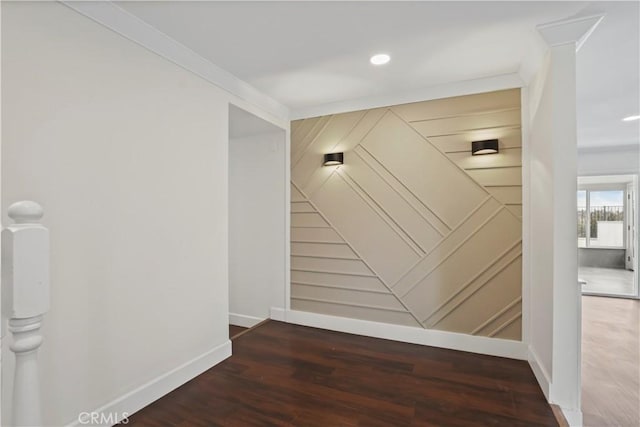 hallway with ornamental molding, baseboards, wood finished floors, a decorative wall, and recessed lighting