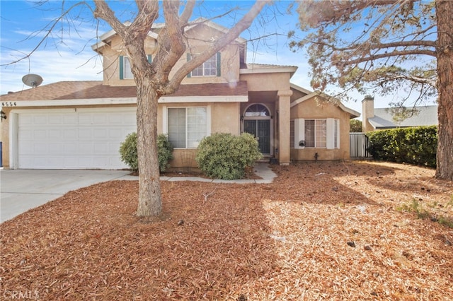 view of front of house with stucco siding, concrete driveway, fence, and a garage