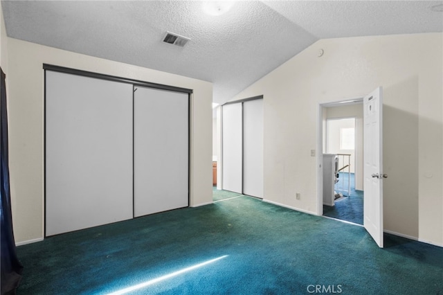 unfurnished bedroom with carpet floors, lofted ceiling, two closets, and a textured ceiling