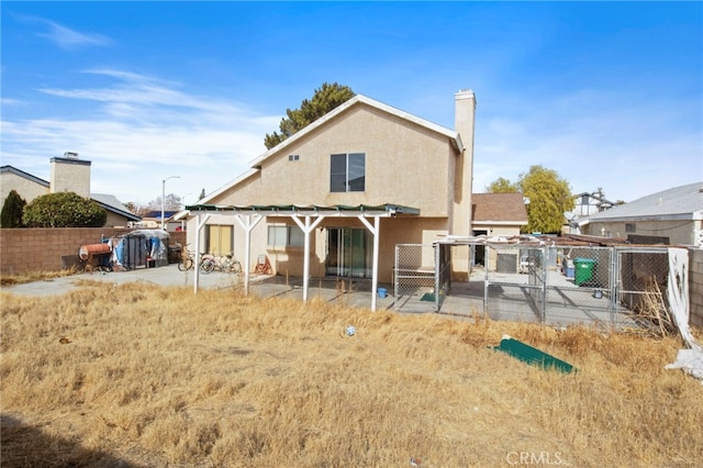 rear view of property with a gate, a fenced backyard, a patio, stucco siding, and a chimney