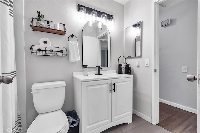 full bath featuring toilet, vanity, and baseboards