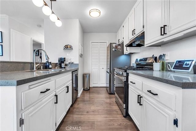 kitchen with gas range, a sink, under cabinet range hood, dark wood-style flooring, and white cabinetry