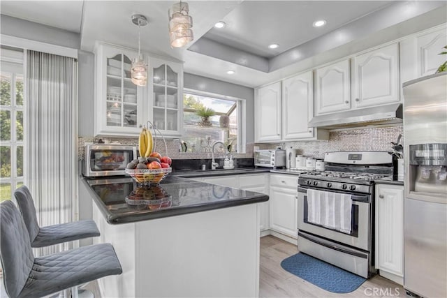 17027 Simonds St, Granada Hills, CA 91344 - kitchen with appliances with stainless steel finishes, dark countertops, under cabinet range hood, white cabinetry, and recessed lighting