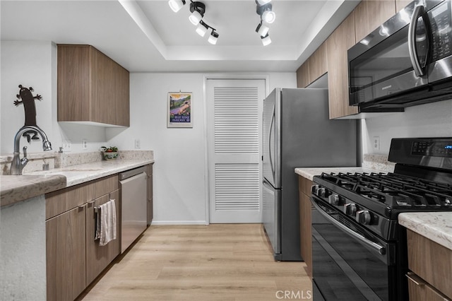 254 E Fern Ave Unit 108, Redlands, CA 92373 - kitchen featuring stainless steel appliances, a sink, light wood-type flooring, a raised ceiling, and baseboards