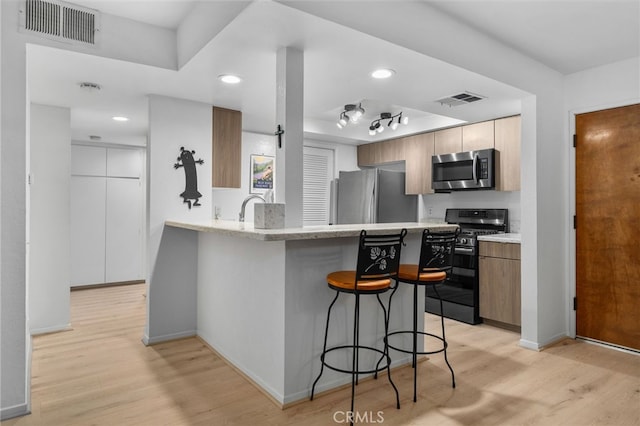 254 E Fern Ave Unit 108, Redlands, CA 92373 - kitchen with stainless steel appliances, light wood finished floors, a breakfast bar area, a peninsula, and recessed lighting