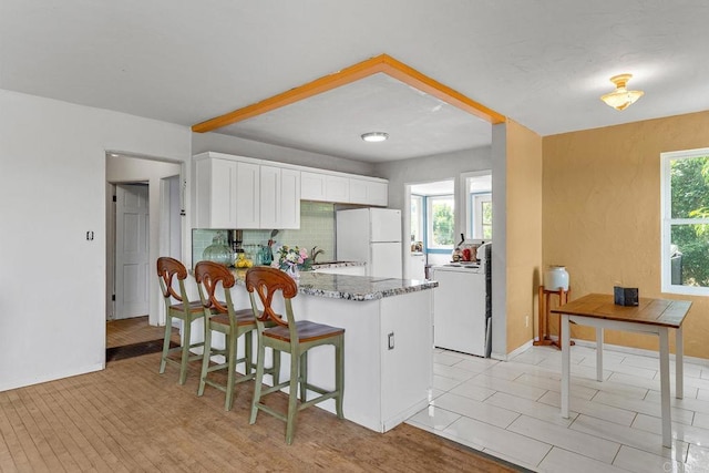 2163 Gracey Ln, Fallbrook, CA 92028 - kitchen featuring freestanding refrigerator, a peninsula, tasteful backsplash, light stone countertops, and white cabinetry