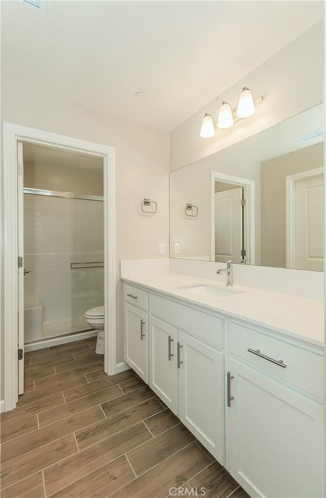 1123 Vanguard Way W, Madera, CA 93636 - bathroom with wood finish floors, toilet, vanity, and an enclosed shower