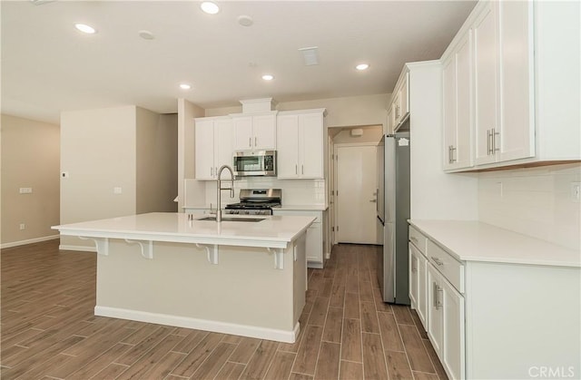 1123 Vanguard Way W, Madera, CA 93636 - kitchen with appliances with stainless steel finishes, a sink, wood finished floors, white cabinets, and recessed lighting