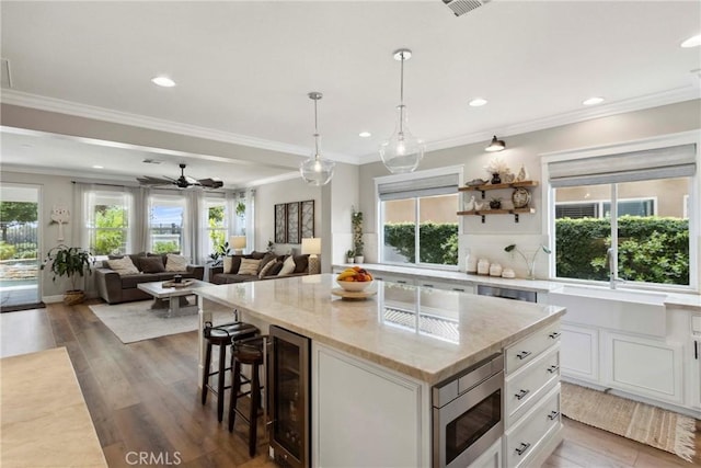 32840 Northshire Cir, Temecula, CA 92592 - kitchen with stainless steel microwave, wine cooler, plenty of natural light, a kitchen breakfast bar, and crown molding