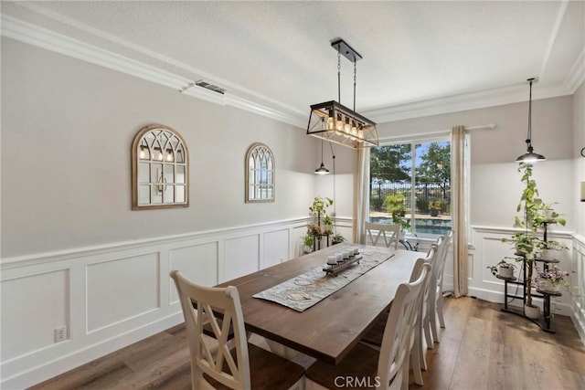 32840 Northshire Cir, Temecula, CA 92592 - dining space with a decorative wall, crown molding, wood finished floors, a wainscoted wall, and a chandelier
