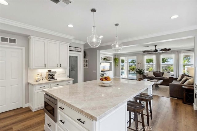 32840 Northshire Cir, Temecula, CA 92592 - kitchen featuring stainless steel microwave, a breakfast bar area, wood finished floors, open floor plan, and a center island