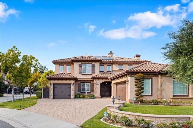 2583 N Skytop Ct, Orange, CA 92867 - mediterranean / spanish house with stucco siding, solar panels, a front yard, an attached garage, and decorative driveway