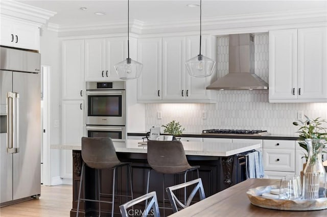 2583 N Skytop Ct, Orange, CA 92867 - kitchen featuring stainless steel appliances, wall chimney exhaust hood, a kitchen breakfast bar, white cabinetry, and crown molding
