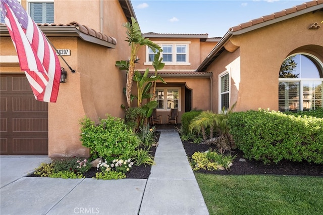 46397 Kohinoor Way, Temecula, CA 92592 - doorway to property featuring a garage, a tile roof, and stucco siding