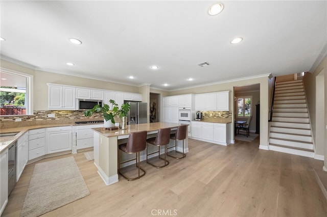 46397 Kohinoor Way, Temecula, CA 92592 - kitchen with stainless steel appliances, backsplash, a center island, a kitchen breakfast bar, and ornamental molding