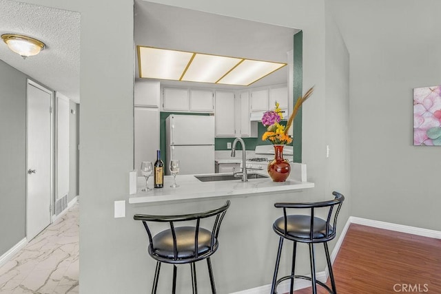 628 Daisy Ave Unit 420, Long Beach, CA 90802 - kitchen featuring white appliances, a sink, a peninsula, light countertops, and a breakfast bar